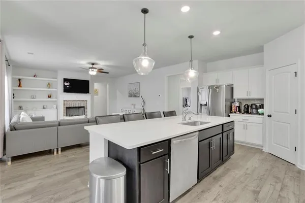 a large white kitchen with a stove a sink a kitchen island with chairs and wooden floor