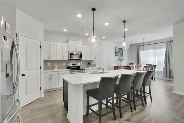 a kitchen with kitchen island a dining table chairs stainless steel appliances and cabinets