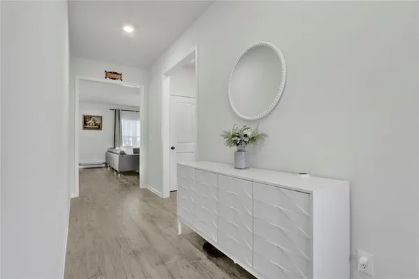 a view of a hallway with wooden floor and a bathroom