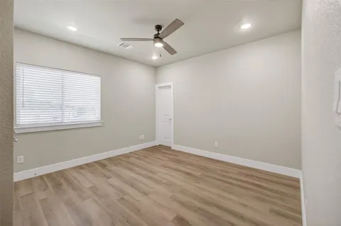 an empty room with wooden floor fan and windows