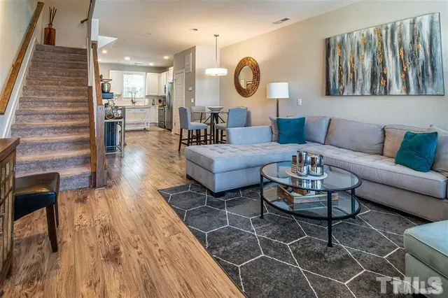 a living room with furniture kitchen view and a wooden floor