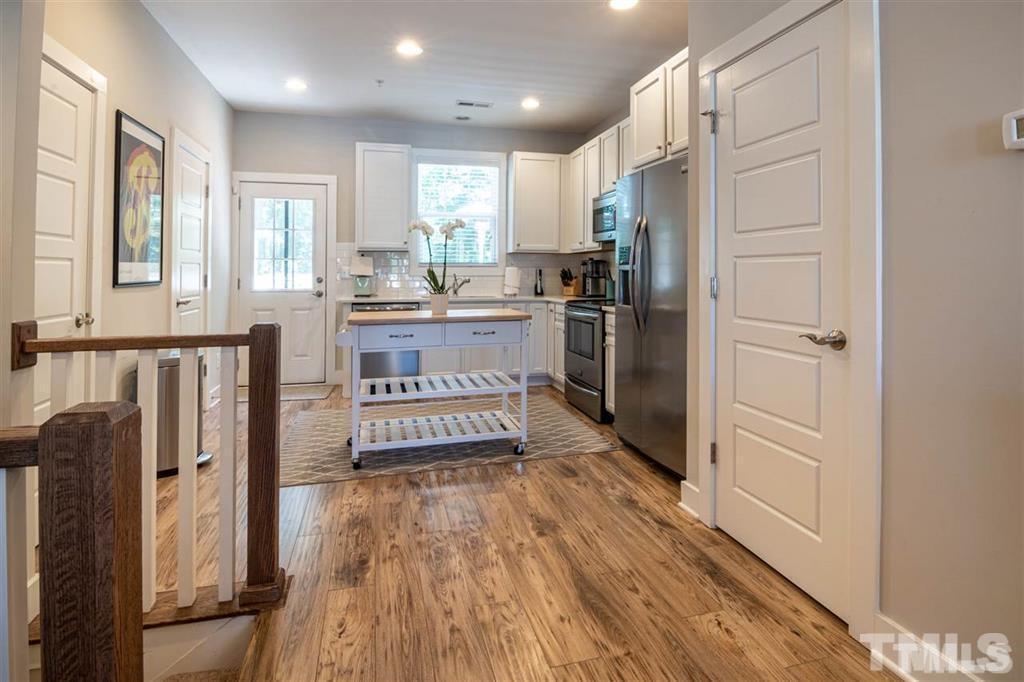 2800 Bedford Green Drive, Unit 106 Raleigh, NC 27604 - Photo 6 of 26 a kitchen with stainless steel appliances granite countertop a refrigerator a stove and a wooden floors