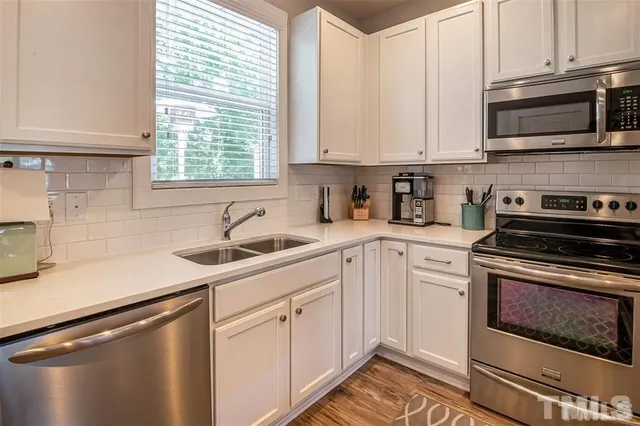 a kitchen with stainless steel appliances granite countertop white cabinets a sink a stove and a microwave
