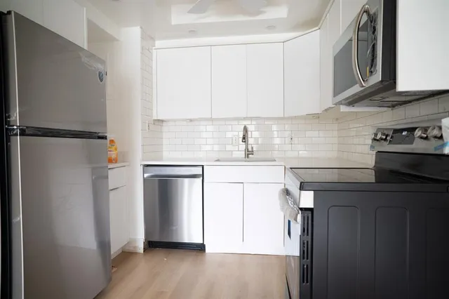 an empty room with wooden floor ceiling fan and windows