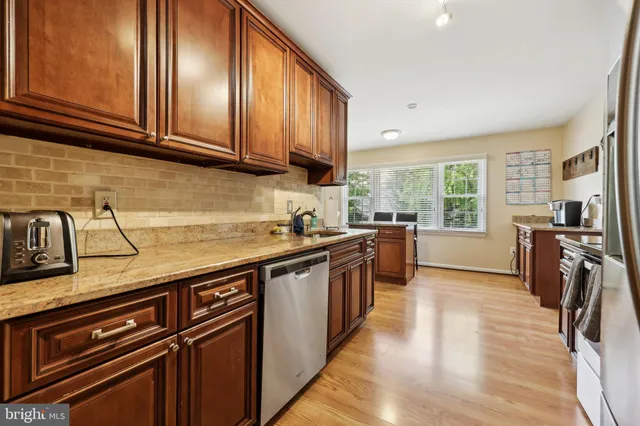 a kitchen with granite countertop wooden cabinets stainless steel appliances a sink and a window