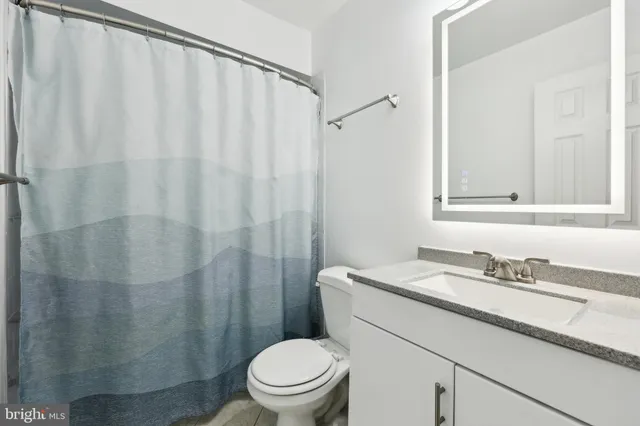 a bathroom with a sink a toilet and shower curtain