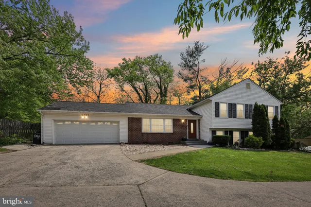 a front view of a house with a garden and trees