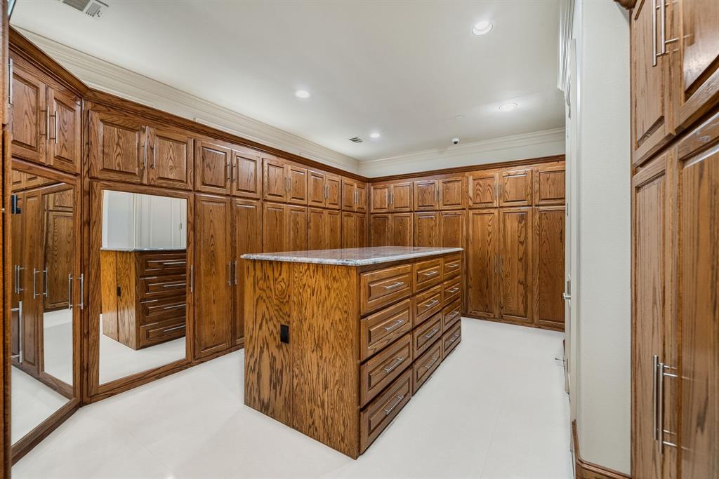 5821 Northaven Road Dallas, TX 75230 - Photo 20 of 40 Custom cabinetry storage system featuring a central island with integrated drawers, granite countertop, and floor-to-ceiling wooden cabinets