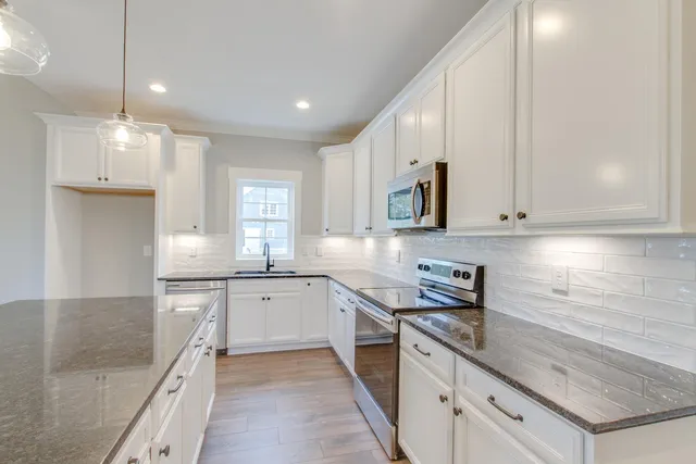 a kitchen with granite countertop a sink a stove and cabinets