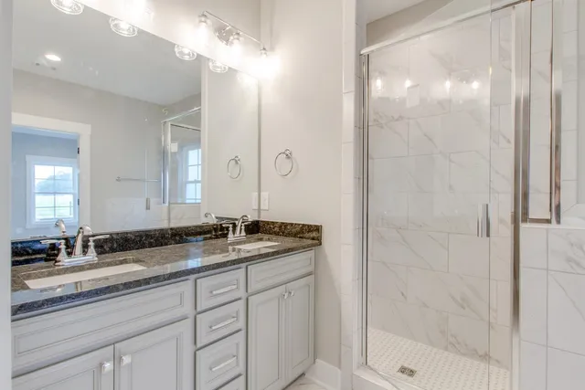 a bathroom with a granite countertop sink a mirror and a shower