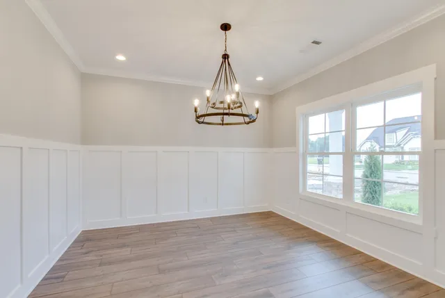 a large room with wooden floor chandelier and windows