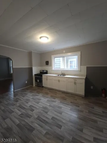 a view of a kitchen and an empty room with wooden floor windows