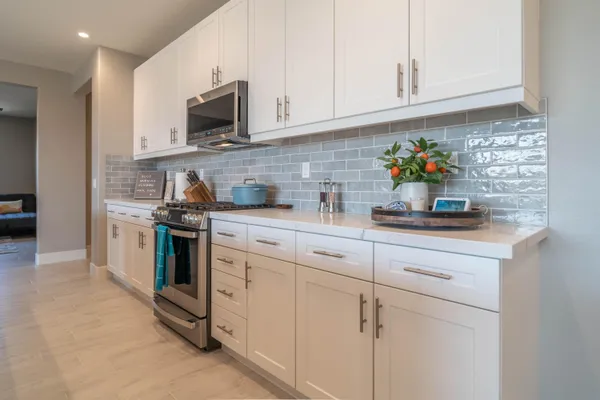 a kitchen with stainless steel appliances granite countertop white cabinets a stove top oven and sink