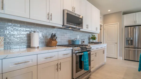 a kitchen with stainless steel appliances granite countertop a refrigerator a stove a sink and white cabinets