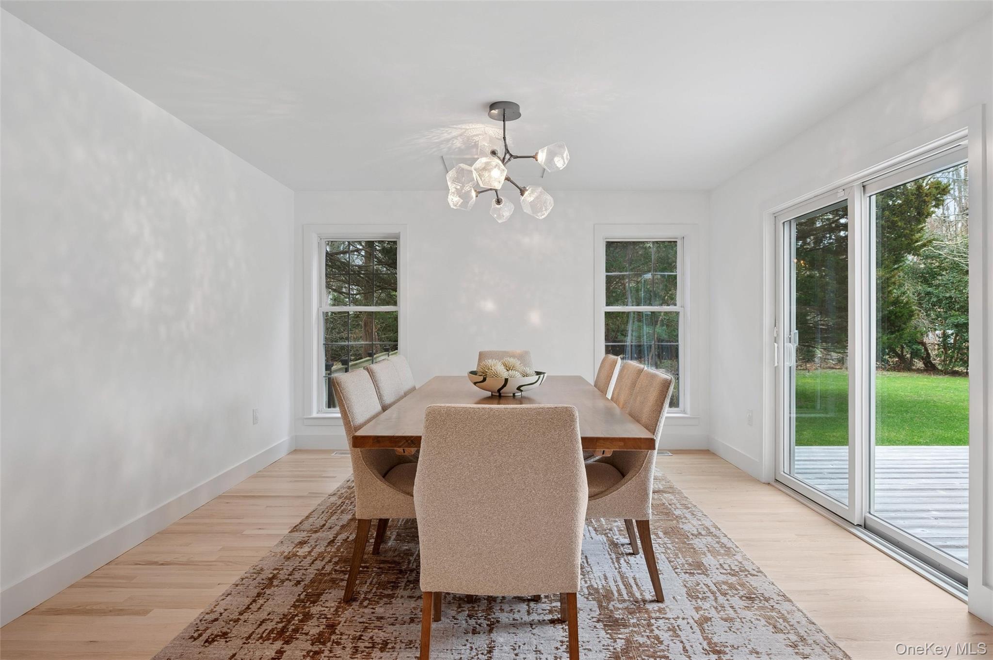 4056 Noyack Road Sag Harbor, NY 11963 - Photo 7 of 21 a dining room with furniture a chandelier and wooden floor