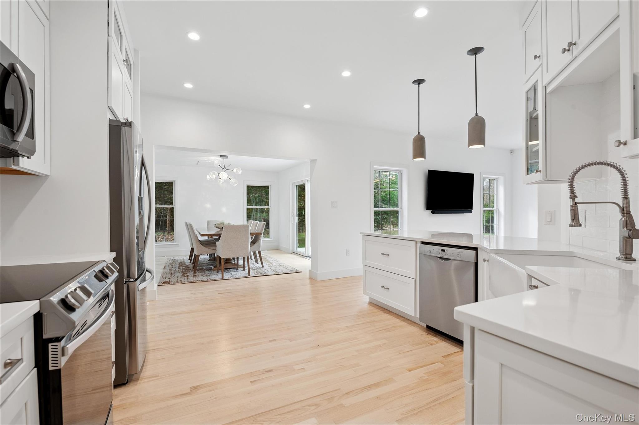 4056 Noyack Road Sag Harbor, NY 11963 - Photo 8 of 21 a kitchen with stainless steel appliances a stove a sink and white cabinets with wooden floor