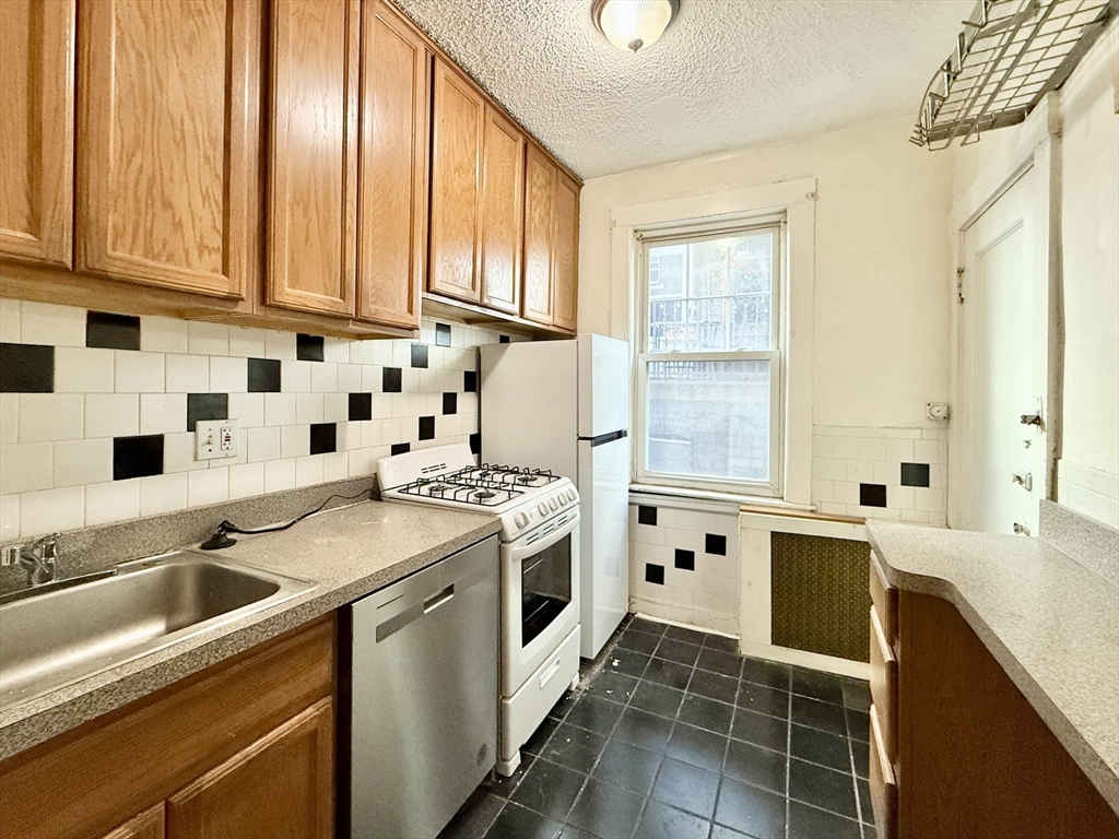 26 Chiswick Road, Unit 6 Boston, MA 02135 - Photo 4 of 19 a kitchen with stainless steel appliances a stove a sink and a microwave