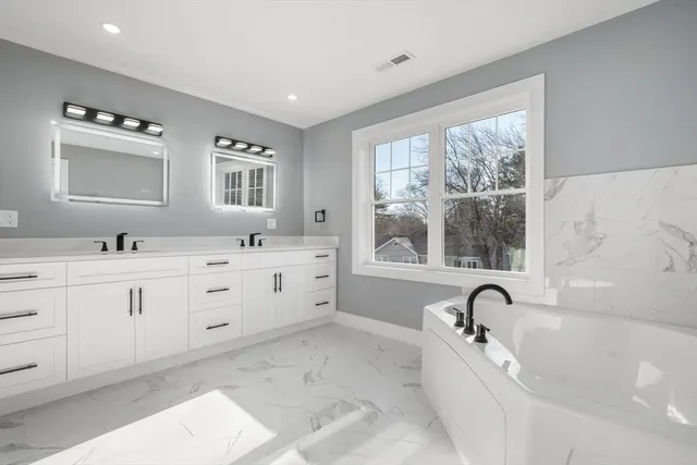 a bathroom with a tub sink and mirror