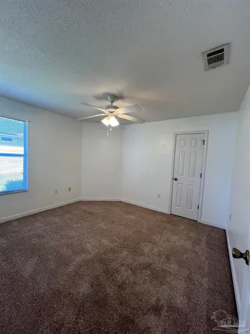 an empty room with a chandelier fan and windows