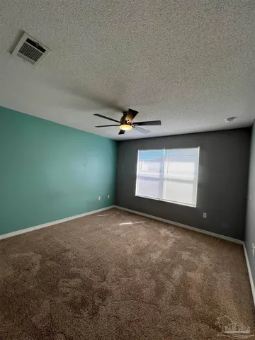 an empty room with windows and fan