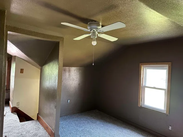an empty room with a fan & a ceiling fan
