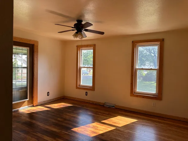 a view of an empty room with wooden floor and a window