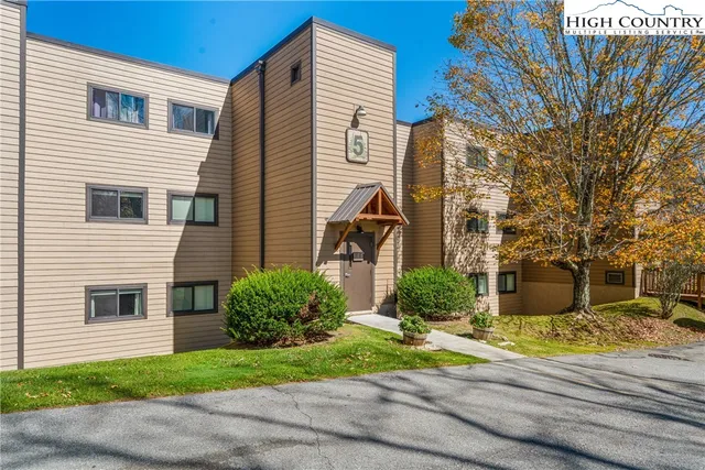 a view of a white house with a yard and large tree