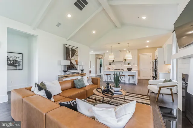 a living room with furniture kitchen view and a wooden floor