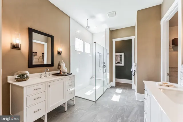 a spacious bathroom with a double vanity sink a large mirror a shower and vanity