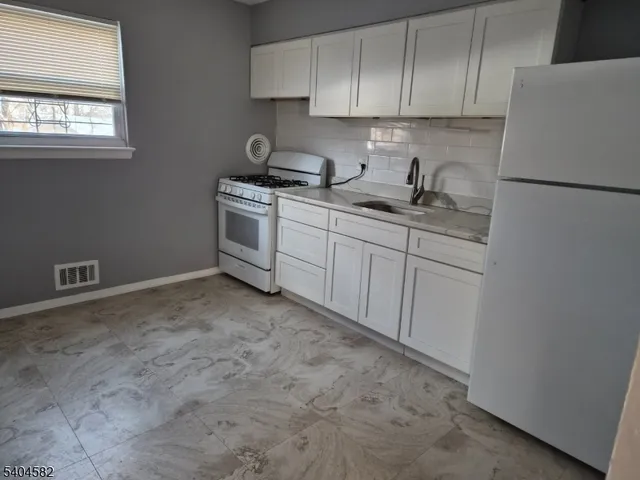 a kitchen with granite countertop white cabinets and white appliances