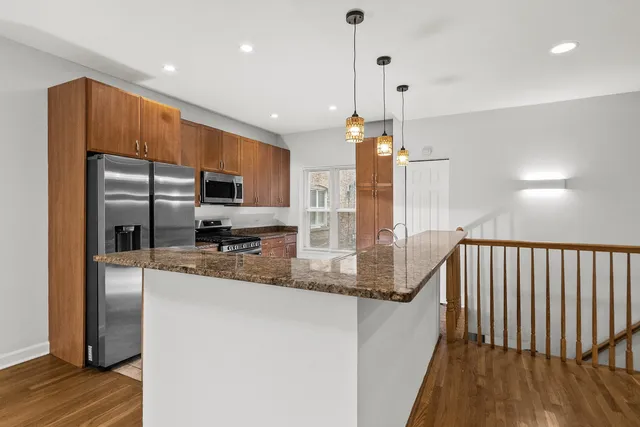 a kitchen with stainless steel appliances granite countertop a refrigerator a sink and a stove