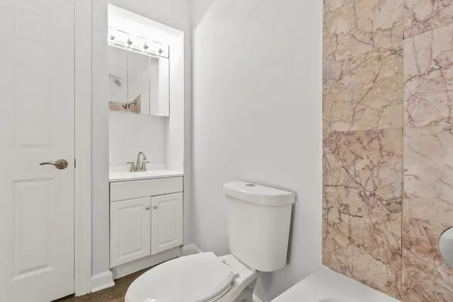 a bathroom with a toilet a sink a mirror and vanity