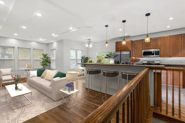 a kitchen with stainless steel appliances granite countertop a stove a sink dishwasher a living room with white cabinets and wooden floor