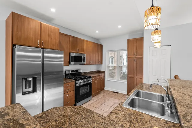 a kitchen with granite countertop a refrigerator stove and sink