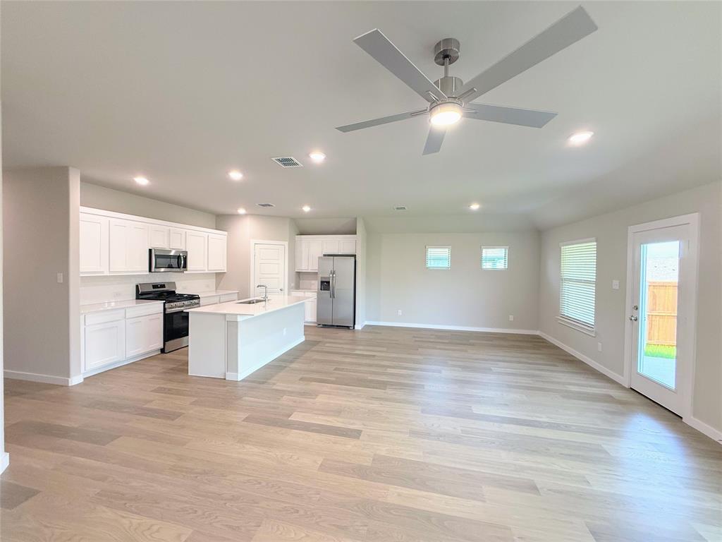 1909 Sandpiper Way Princeton, TX 75407 - Photo 35 of 35 Kitchen featuring stainless steel appliances, open floor plan, recessed lighting, white cabinets, and an island with sink