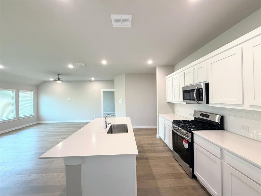 1909 Sandpiper Way Princeton, TX 75407 - Photo 8 of 35 Kitchen with stainless steel appliances, white cabinetry, recessed lighting, an island with sink, and dark wood finished floors