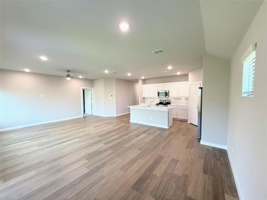 1909 Sandpiper Way Princeton, TX 75407 - Photo 33 of 35 Kitchen featuring open floor plan, a kitchen island with sink, white cabinetry, stainless steel appliances, and recessed lighting