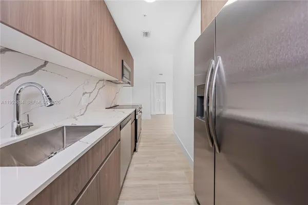 a kitchen with kitchen island granite countertop a sink and refrigerator