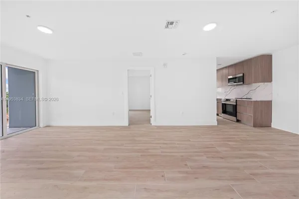 a view of empty room with kitchen and sink