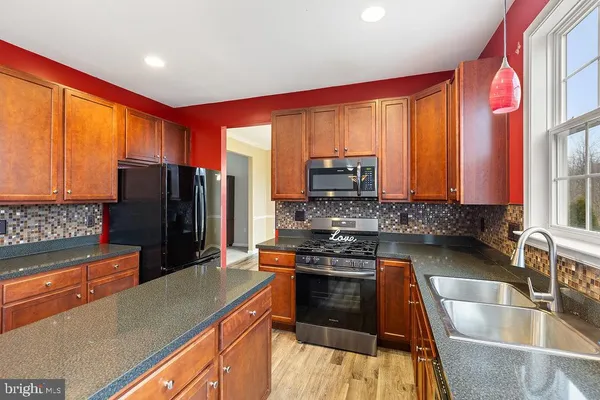 a kitchen with stainless steel appliances granite countertop a refrigerator a stove top oven a sink and dishwasher