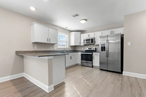 a kitchen with granite countertop a refrigerator sink and cabinets