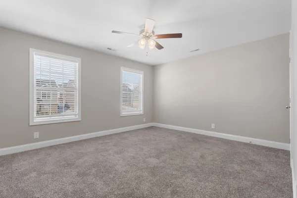 an empty room with windows and fan