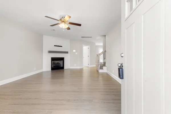 a view of an empty room with a ceiling fan and kitchen view