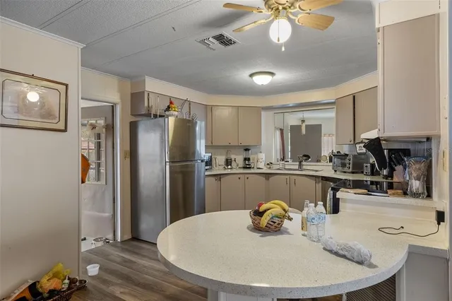a kitchen with stainless steel appliances granite countertop a sink a refrigerator and chairs