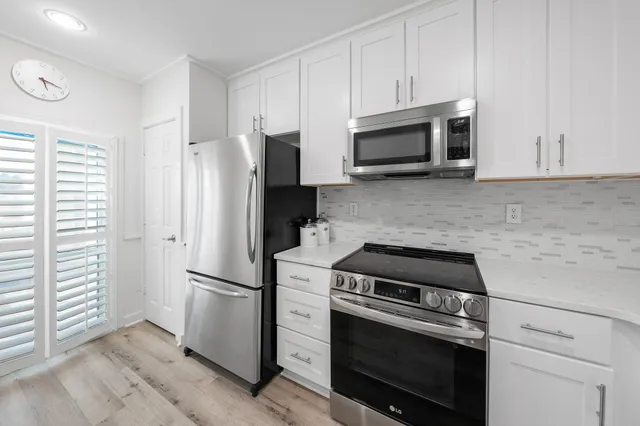 a kitchen with stainless steel appliances granite countertop a stove a kitchen island a dining table and chairs with wooden floor