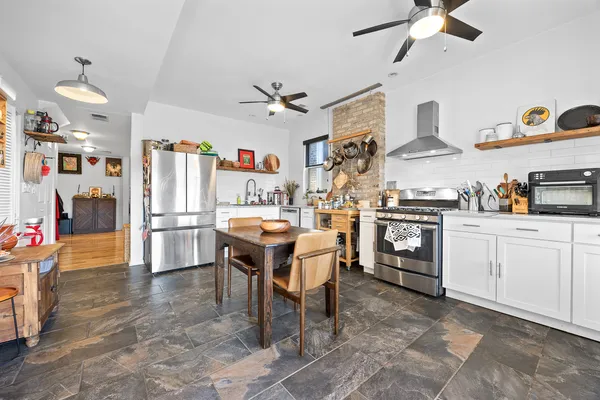 a kitchen with stainless steel appliances kitchen island granite countertop a table chairs in it and wooden floors