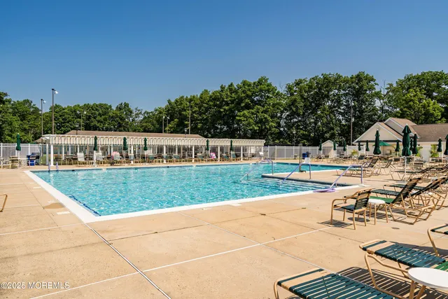 a view of swimming pool with outdoor seating and trees in the background