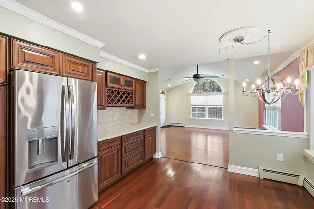 a kitchen with stainless steel appliances granite countertop a refrigerator a sink and wooden floors