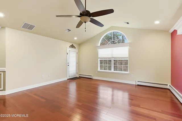 a view of an empty room with a window and wooden floor