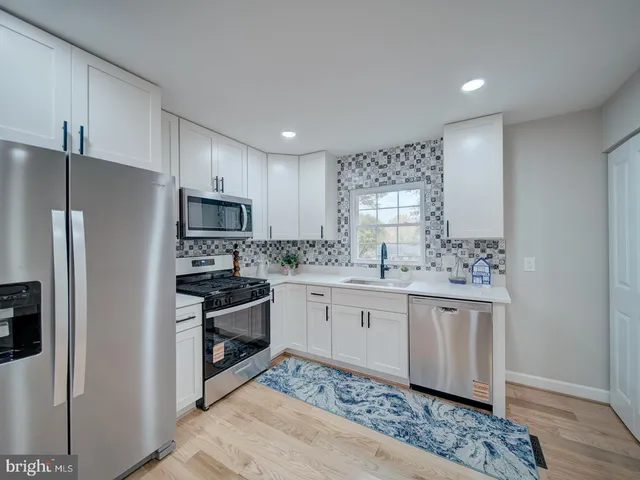 a kitchen with granite countertop white cabinets and stainless steel appliances